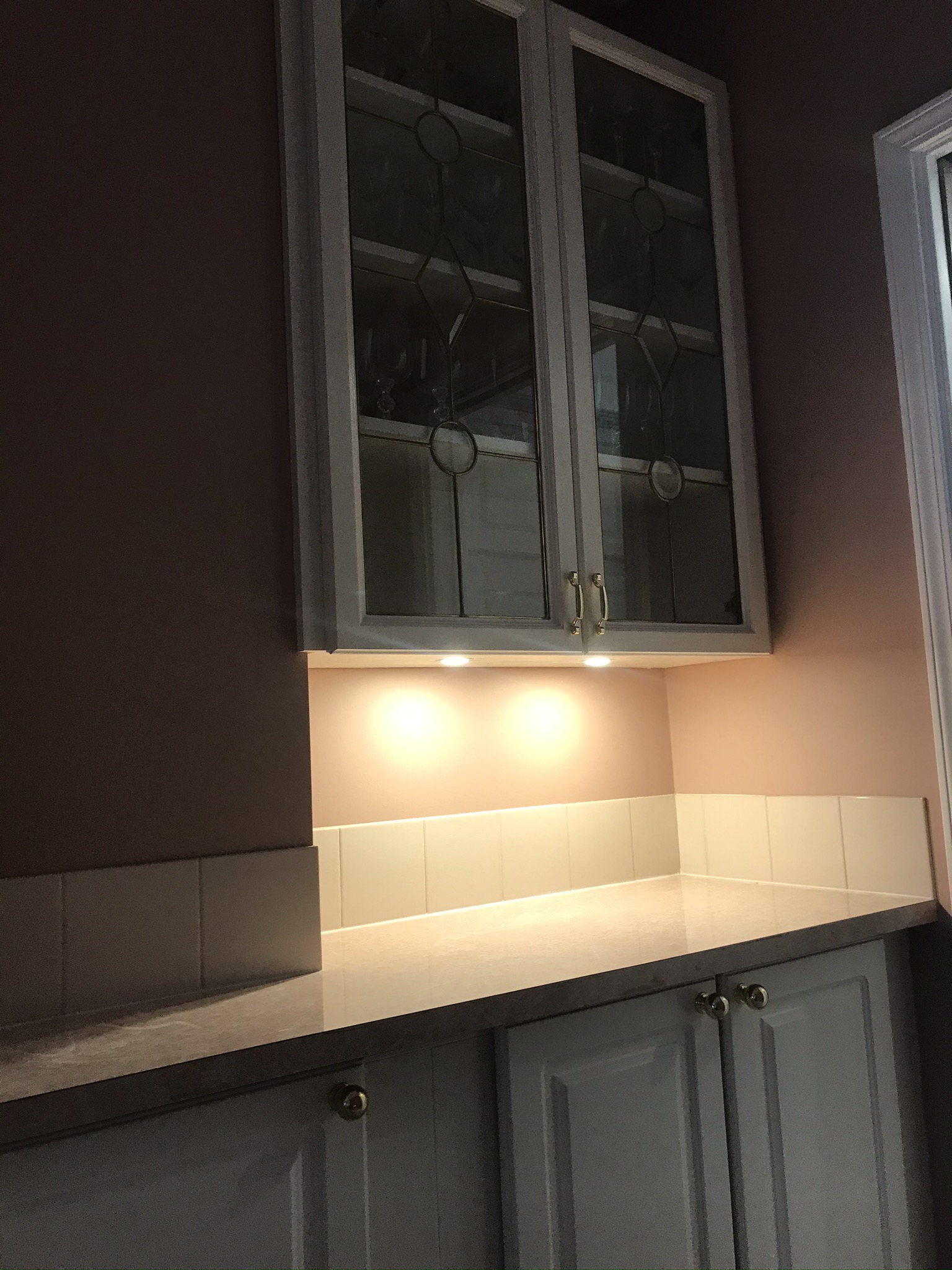 Butler's pantry with under-cabinet puck lights and leaded glass cabinet doors