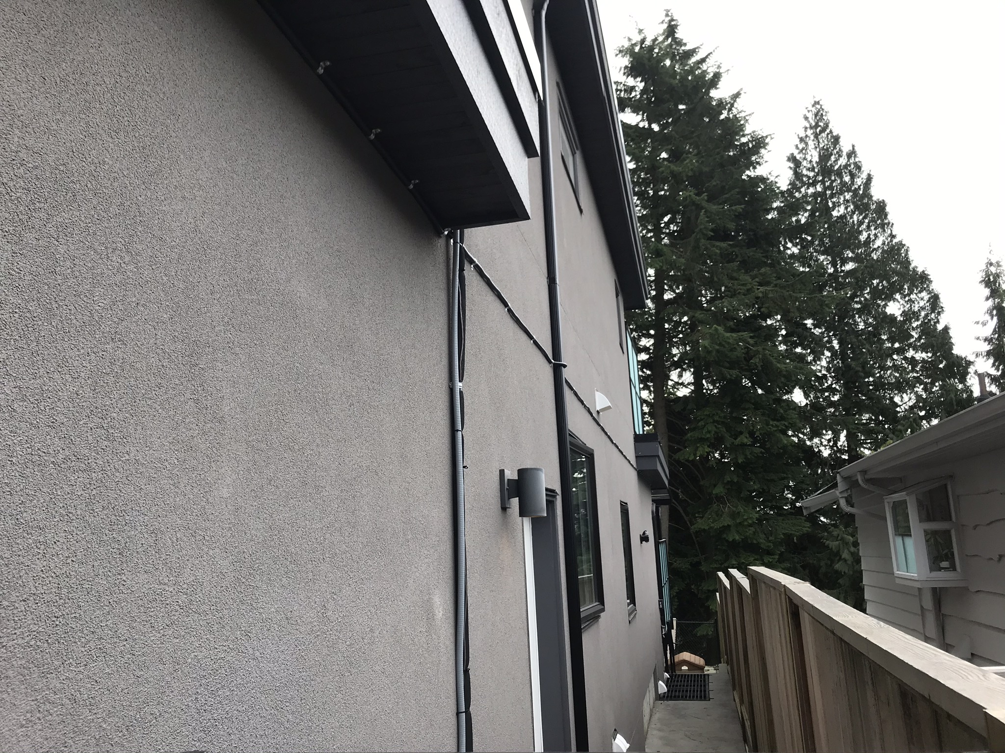 Exterior conduit run with wall sconce on stucco house