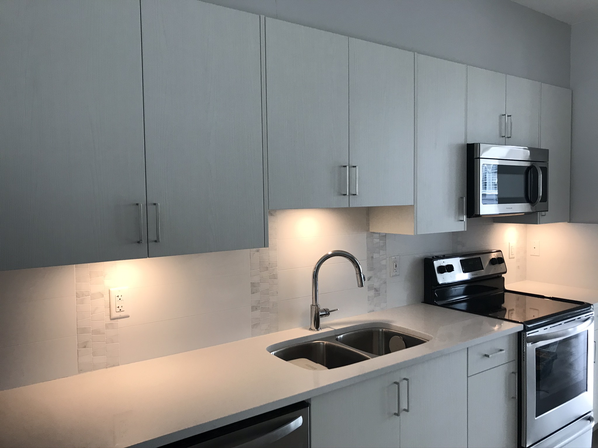 Under-cabinet LED lighting on white quartz kitchen counters