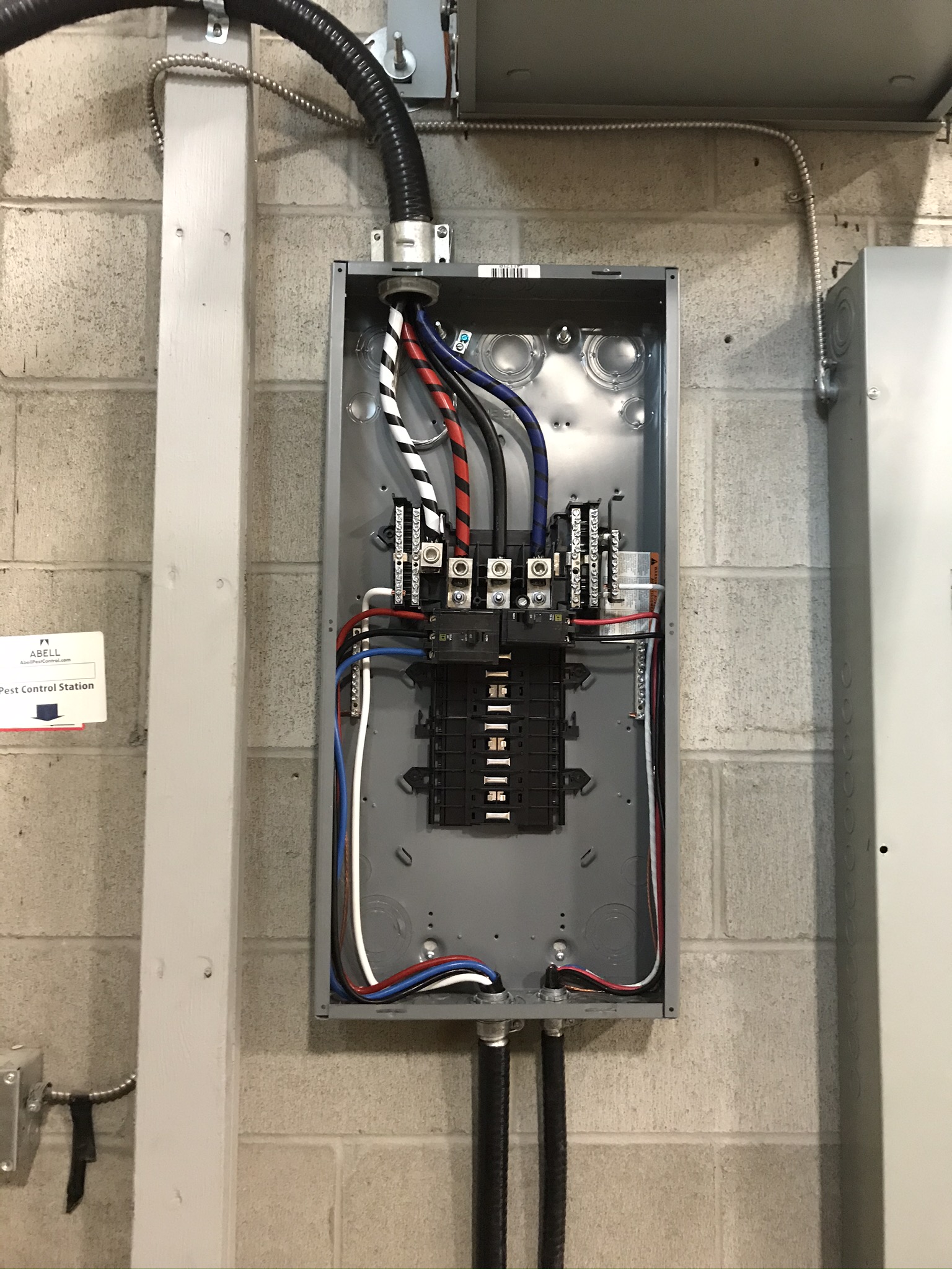 Commercial sub-panel on concrete wall with neat organized wiring