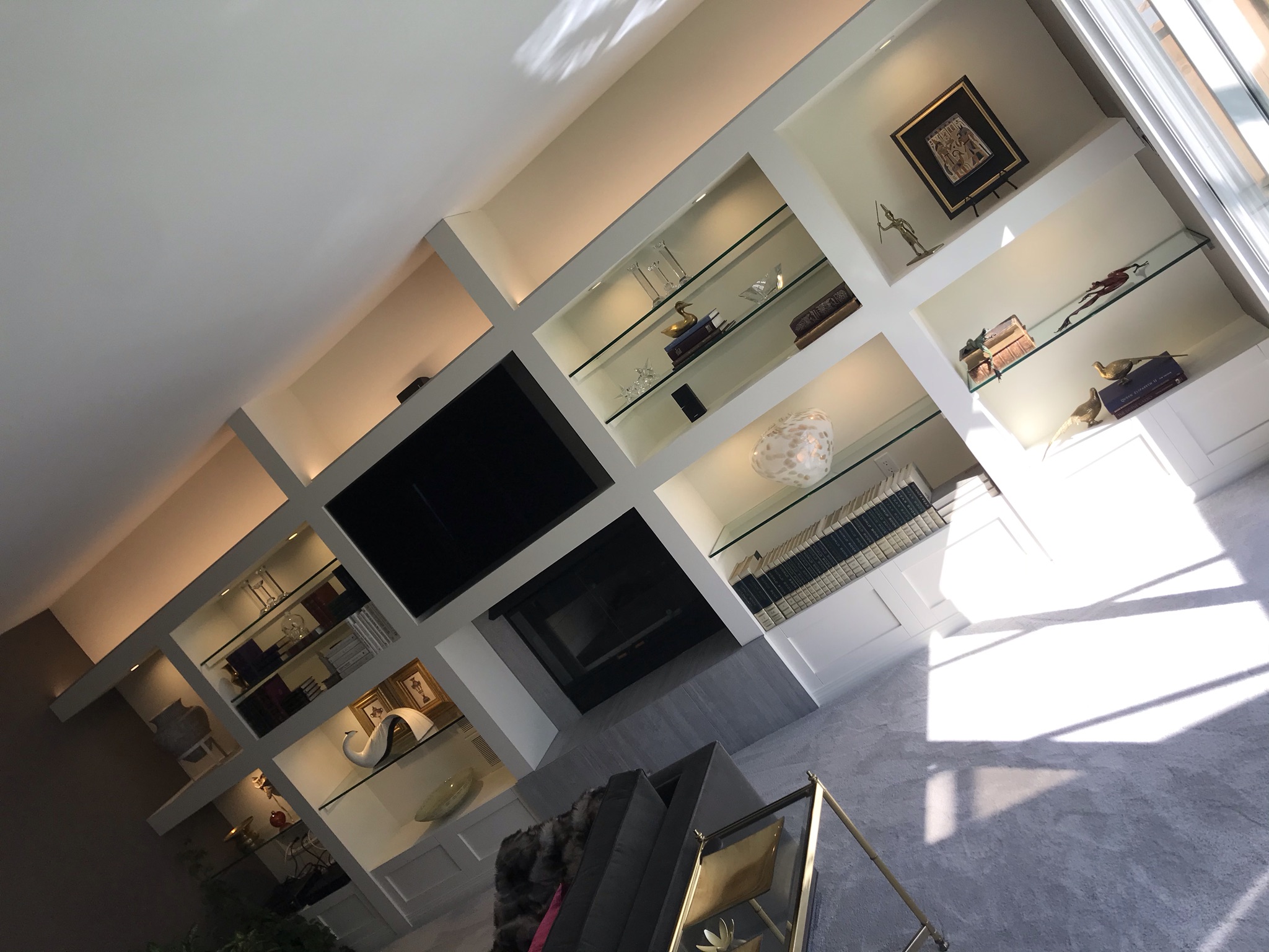 Built-in wall unit with lit glass shelves and TV cove lighting