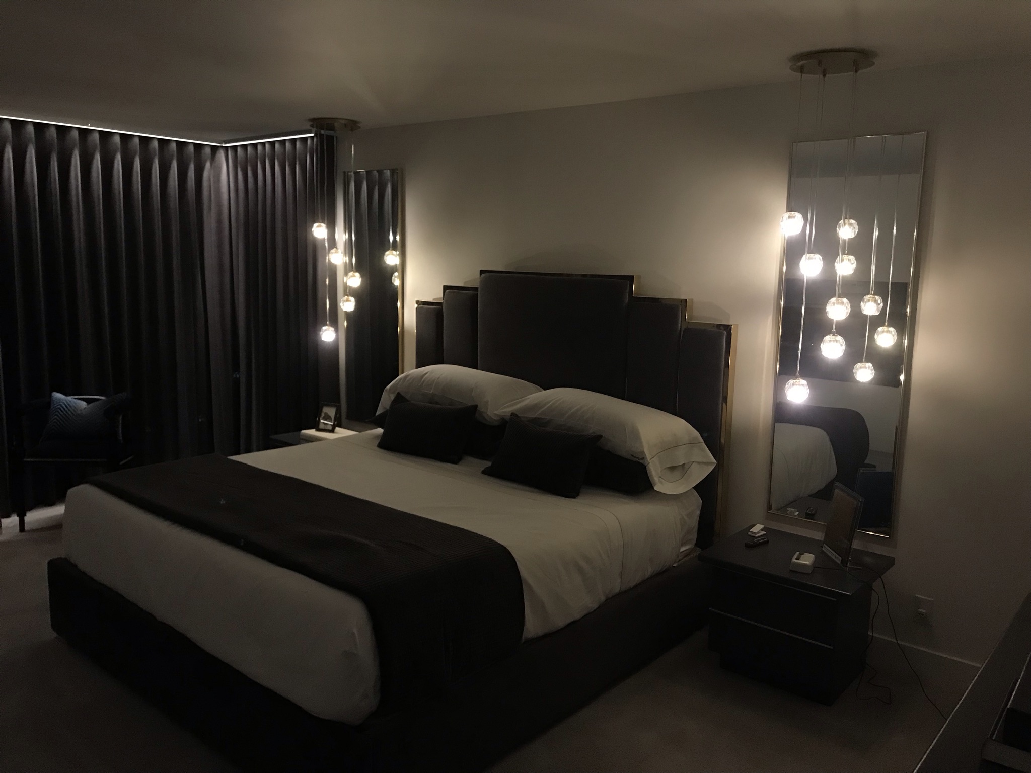 Luxury master suite in moody dark lighting with pendant cluster glow